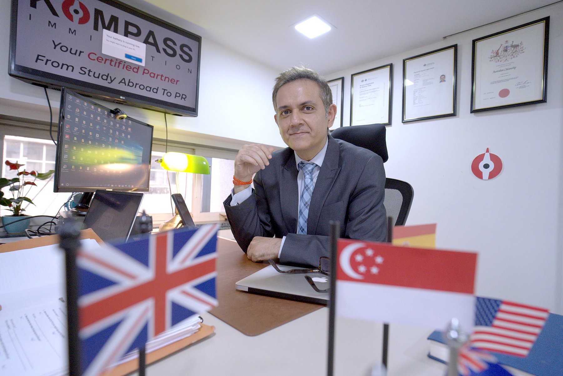 Sumit Kumar smiling at his desk behind country flags